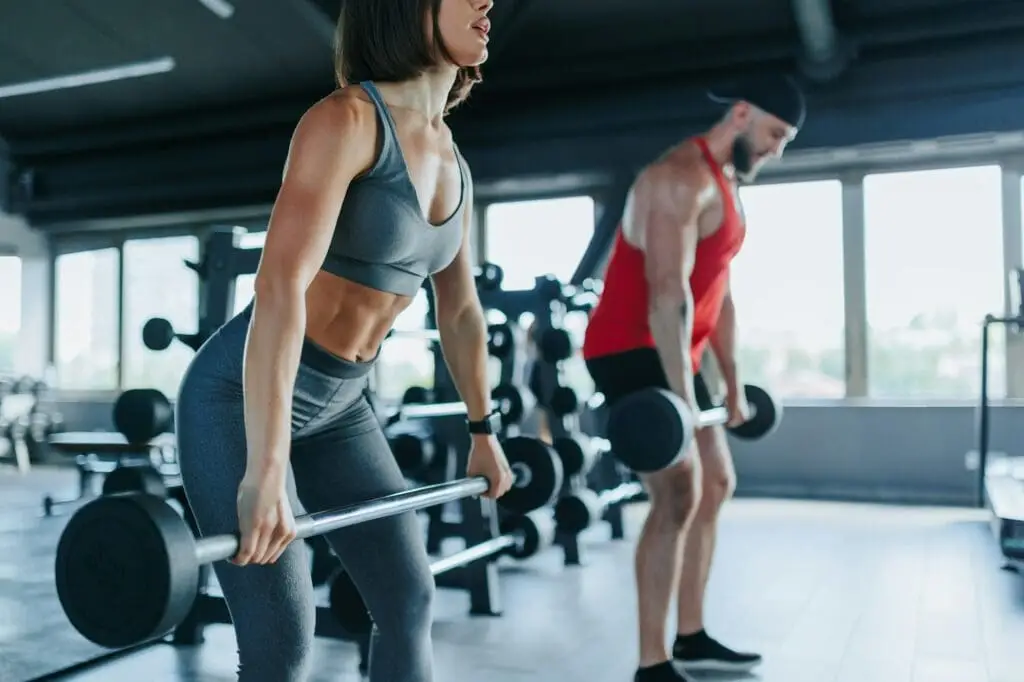 Power Couple Young Man and Woman Lift Weights in the Gym