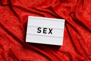 sex - flat lay with text on light box on red velvet bed sheet
