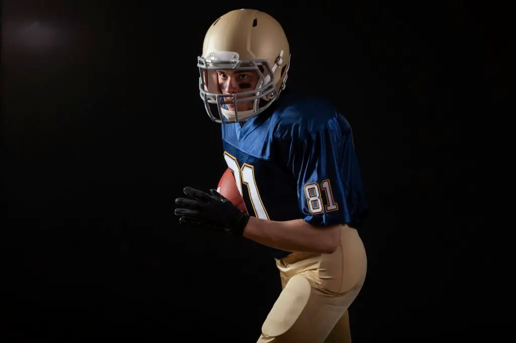 Young football player in running action on a dark background